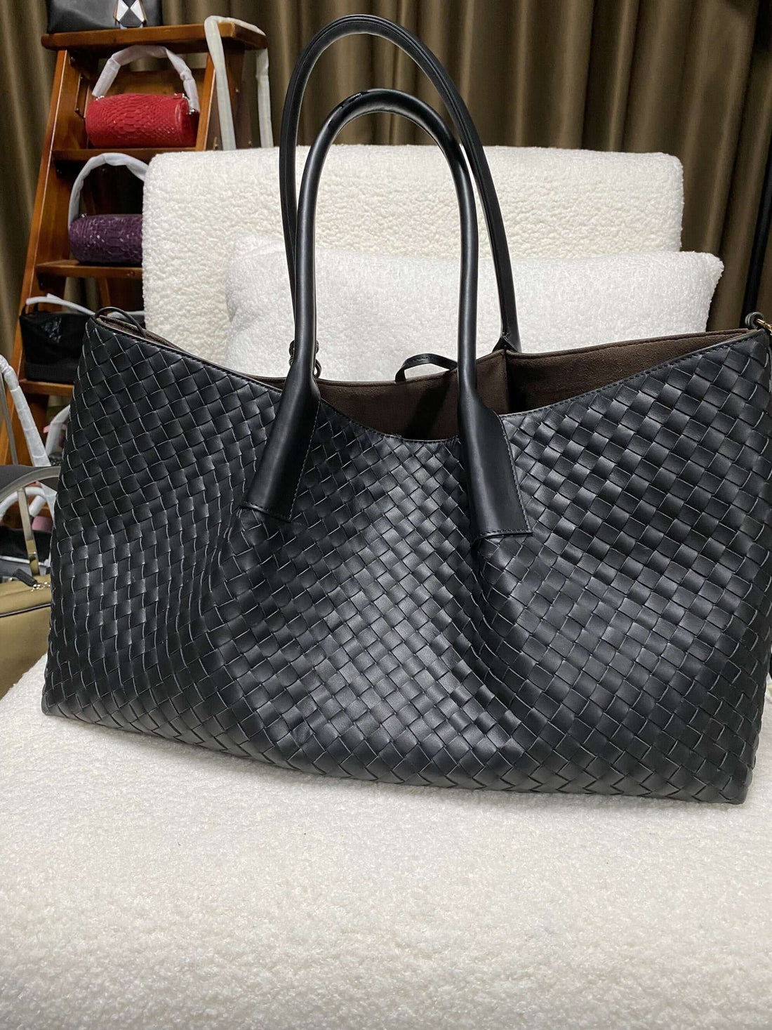 Logo-free top-grain cowhide woven tote — black back view on a white chair