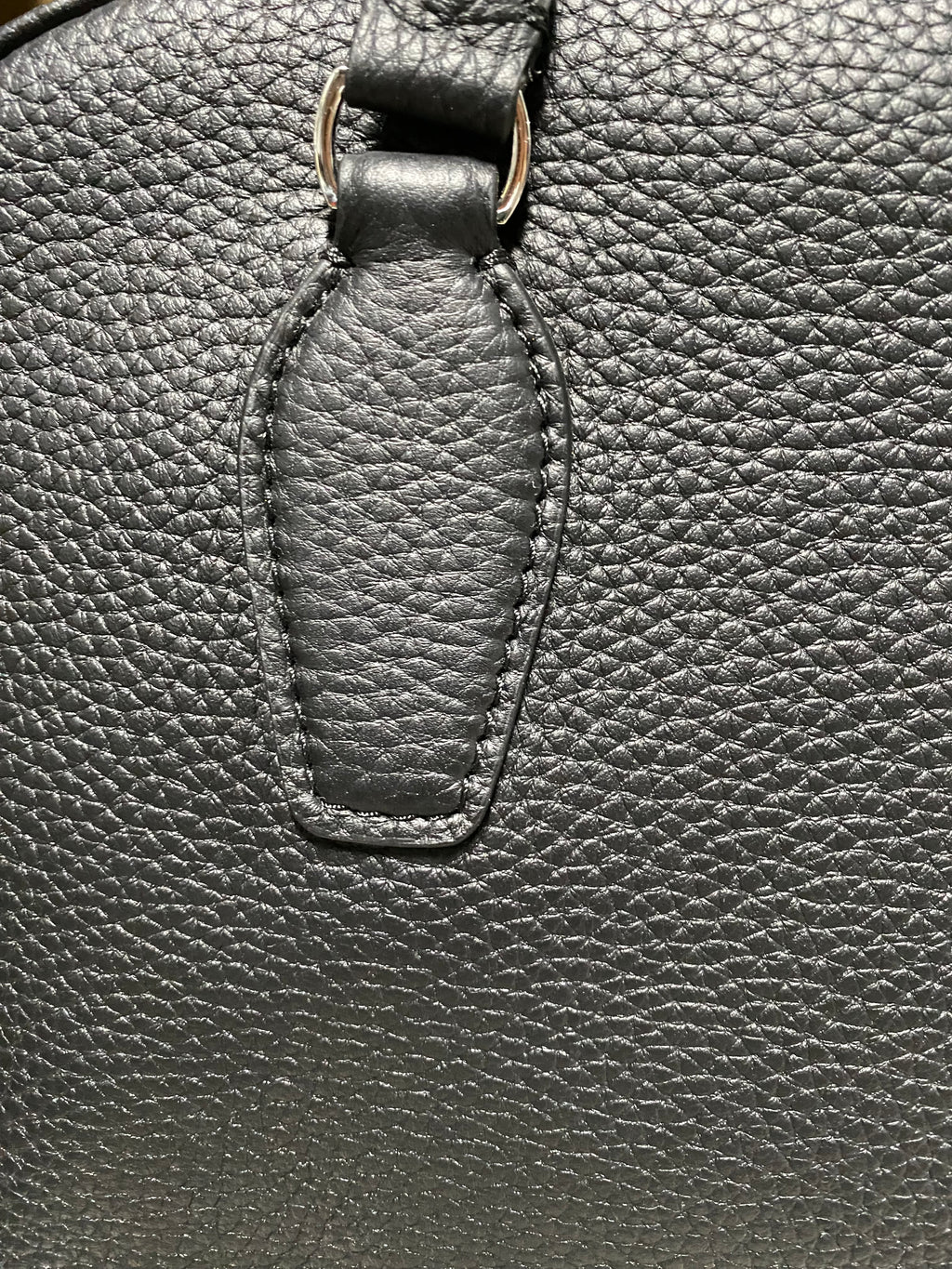 Logo-free full-grain cowhide top-handle bag — stitched handle base close-up