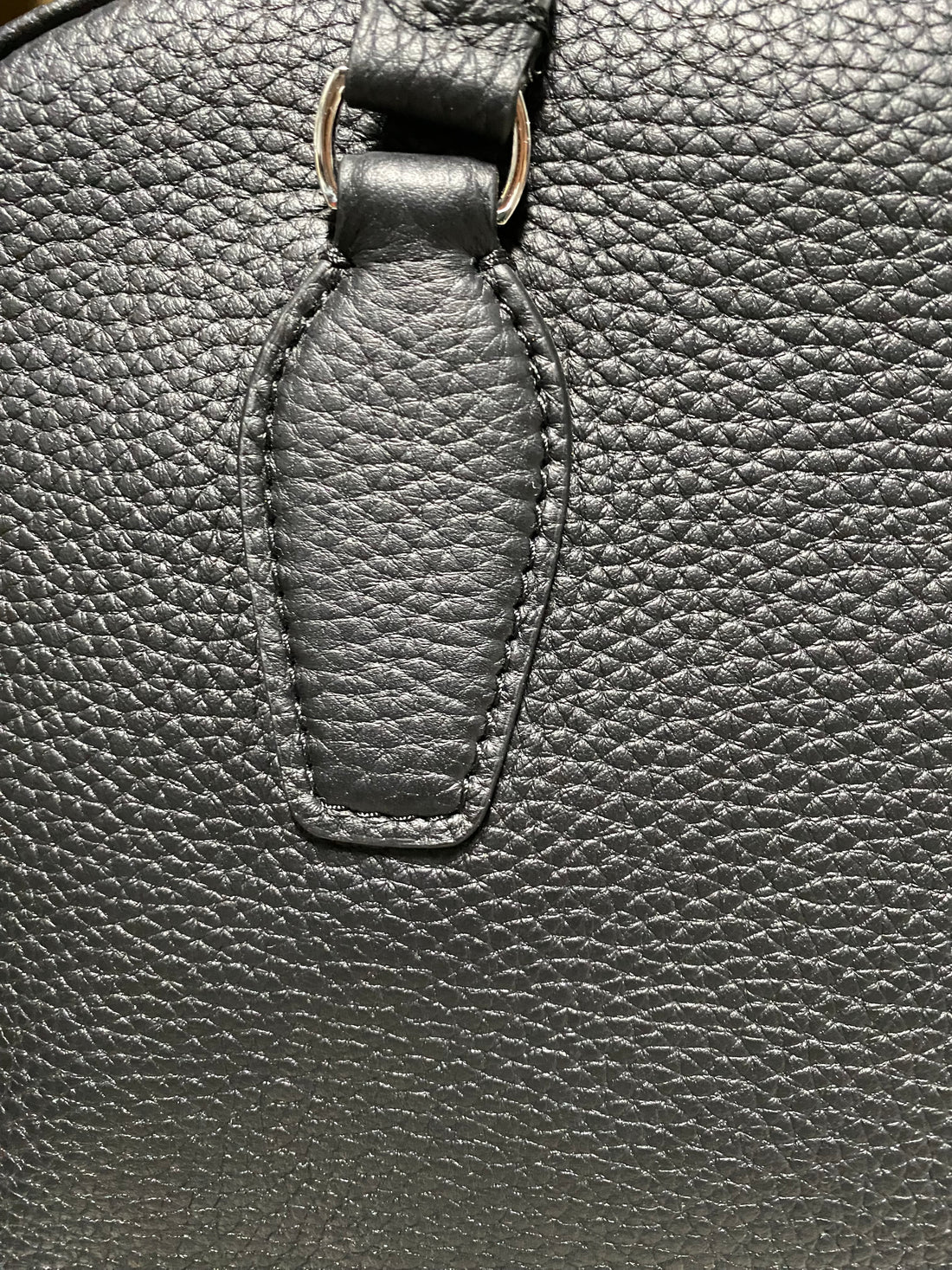 Logo-free full-grain cowhide top-handle bag — stitched handle base close-up