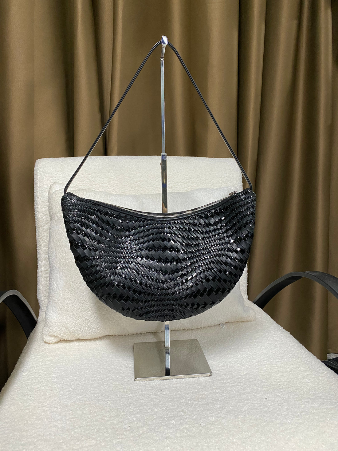 Black slouchy woven leather shoulder bag hanging on display