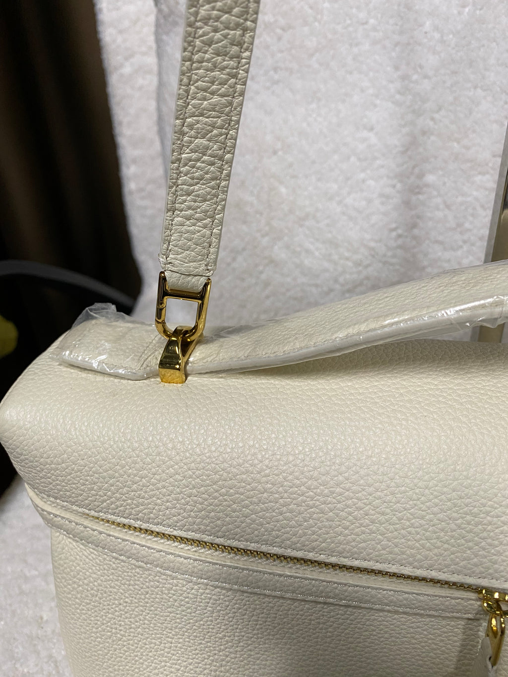 Gold strap clasp on cream white leather shoulder bag