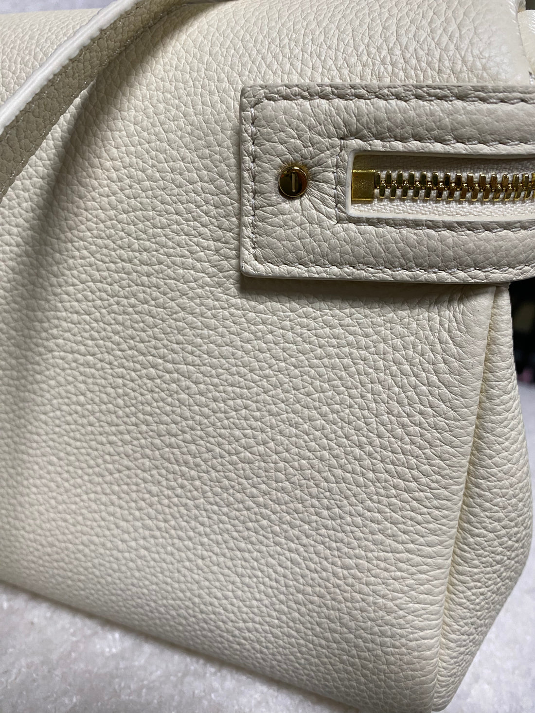 Exterior zipper pocket on cream white pebbled leather handbag