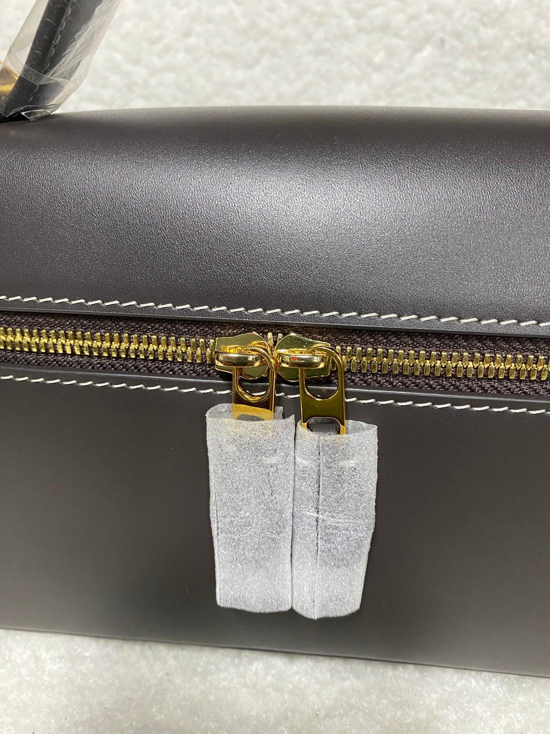 Gold double zipper pulls on dark brown calfskin box handbag