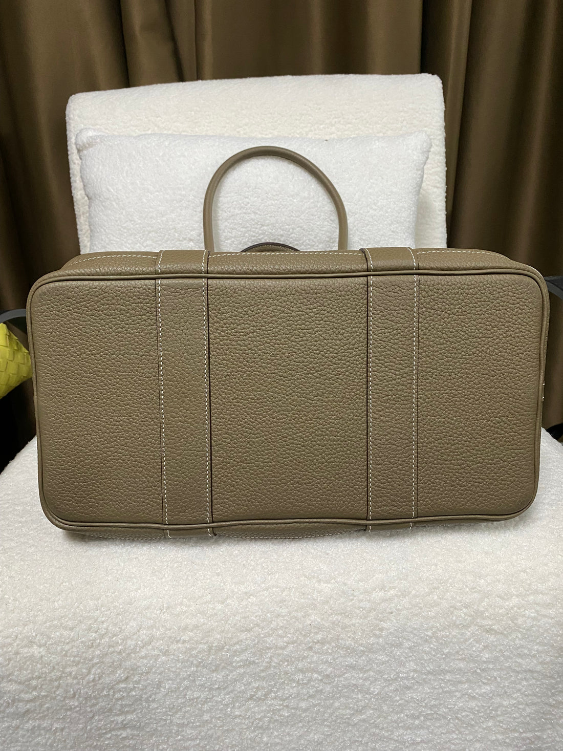Reinforced base of taupe pebbled leather tote on display