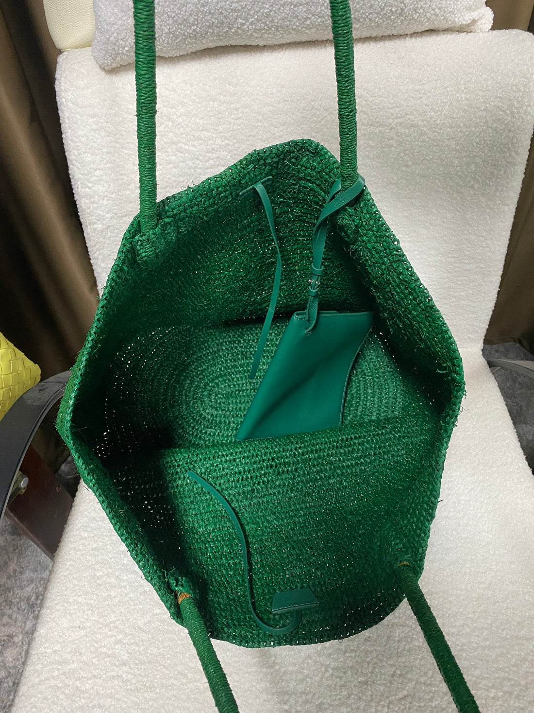 Open emerald green raffia tote showing the interior and matching leather pouch