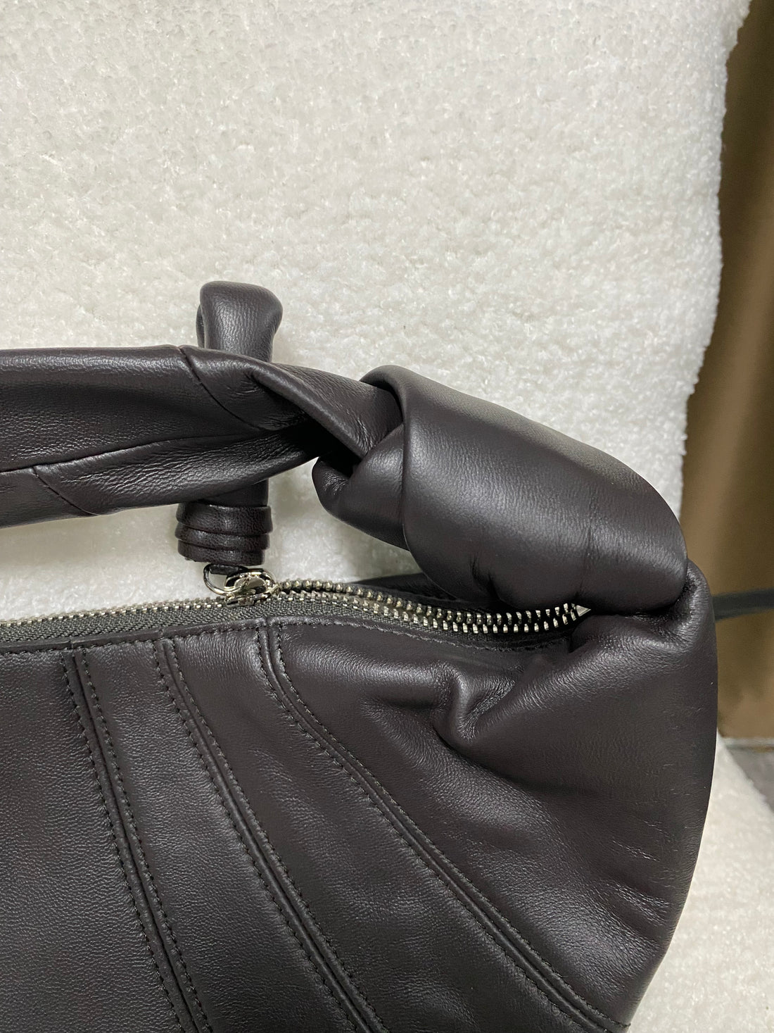 Zip-top closure and knotted handle on black lambskin hobo bag