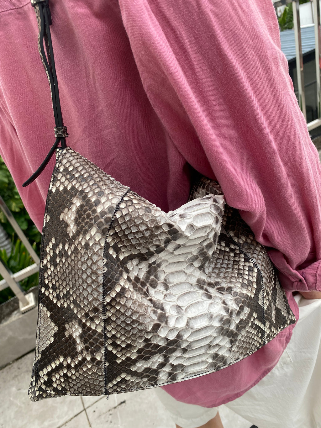 Brown genuine python leather shoulder bag — natural python version worn against a pink shirt