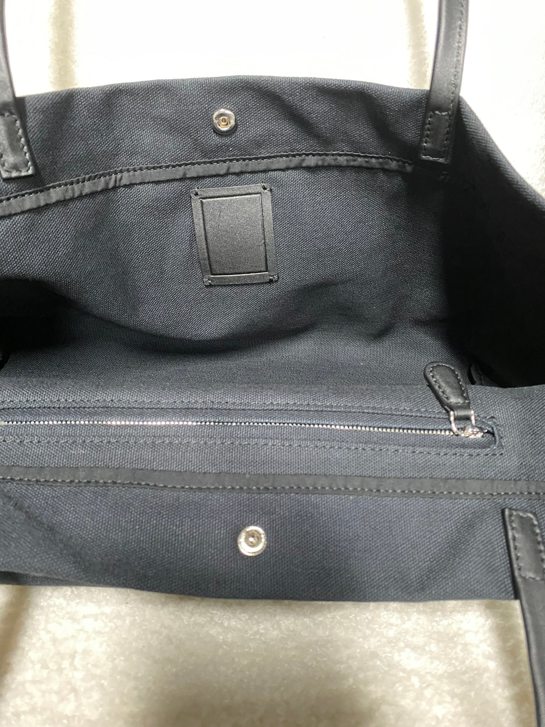 Interior zipper pocket and snap closure inside navy canvas tote