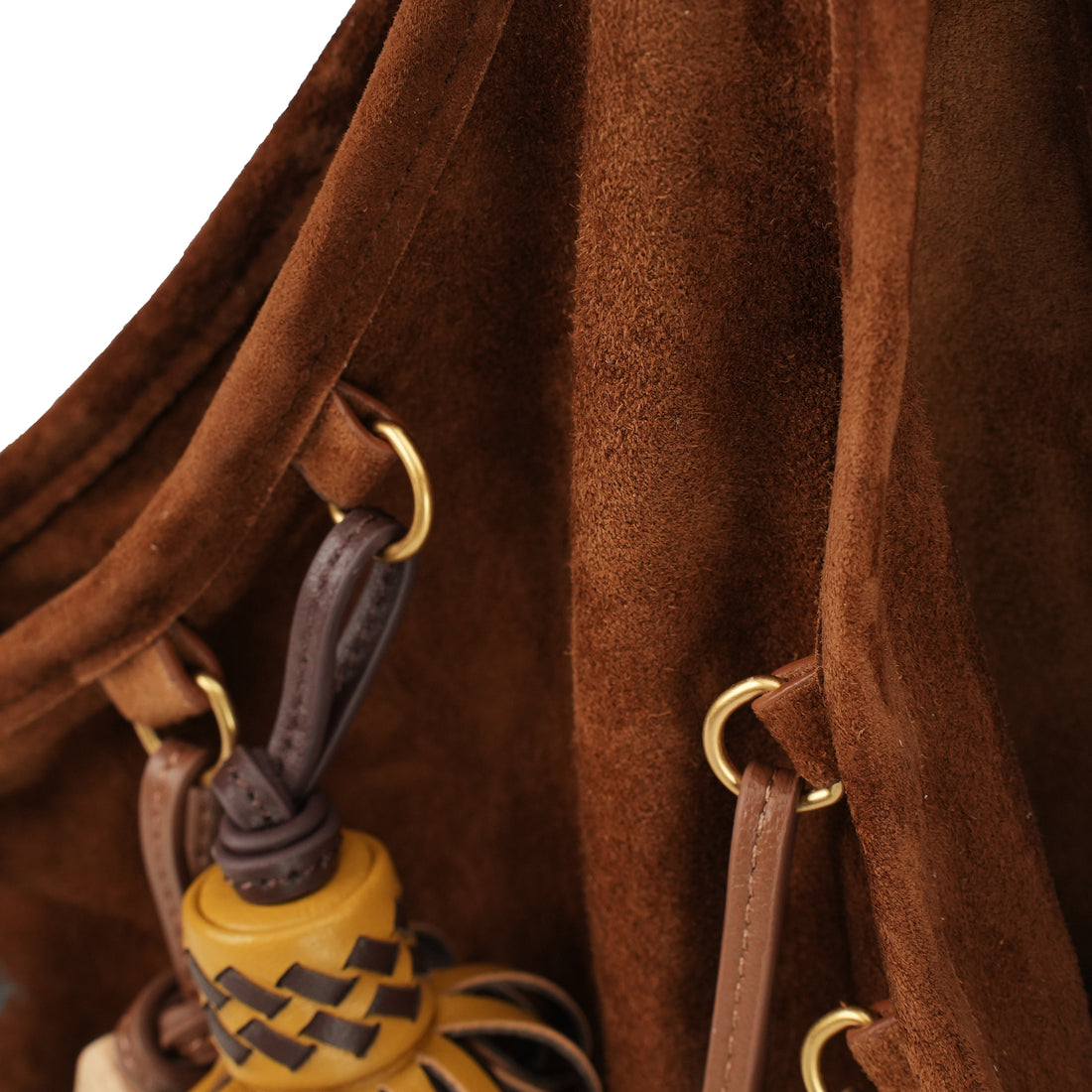 Mustard leather tote with artisan charms — suede seam and charm attachment close-up