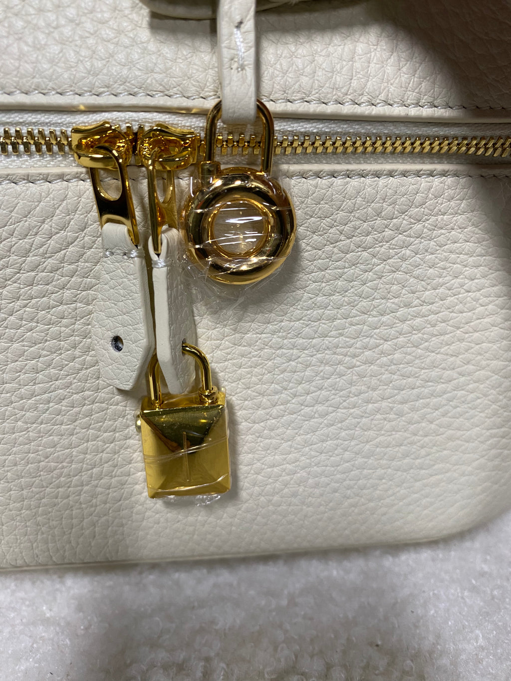 Gold zipper and lock charms on cream vanity case bag