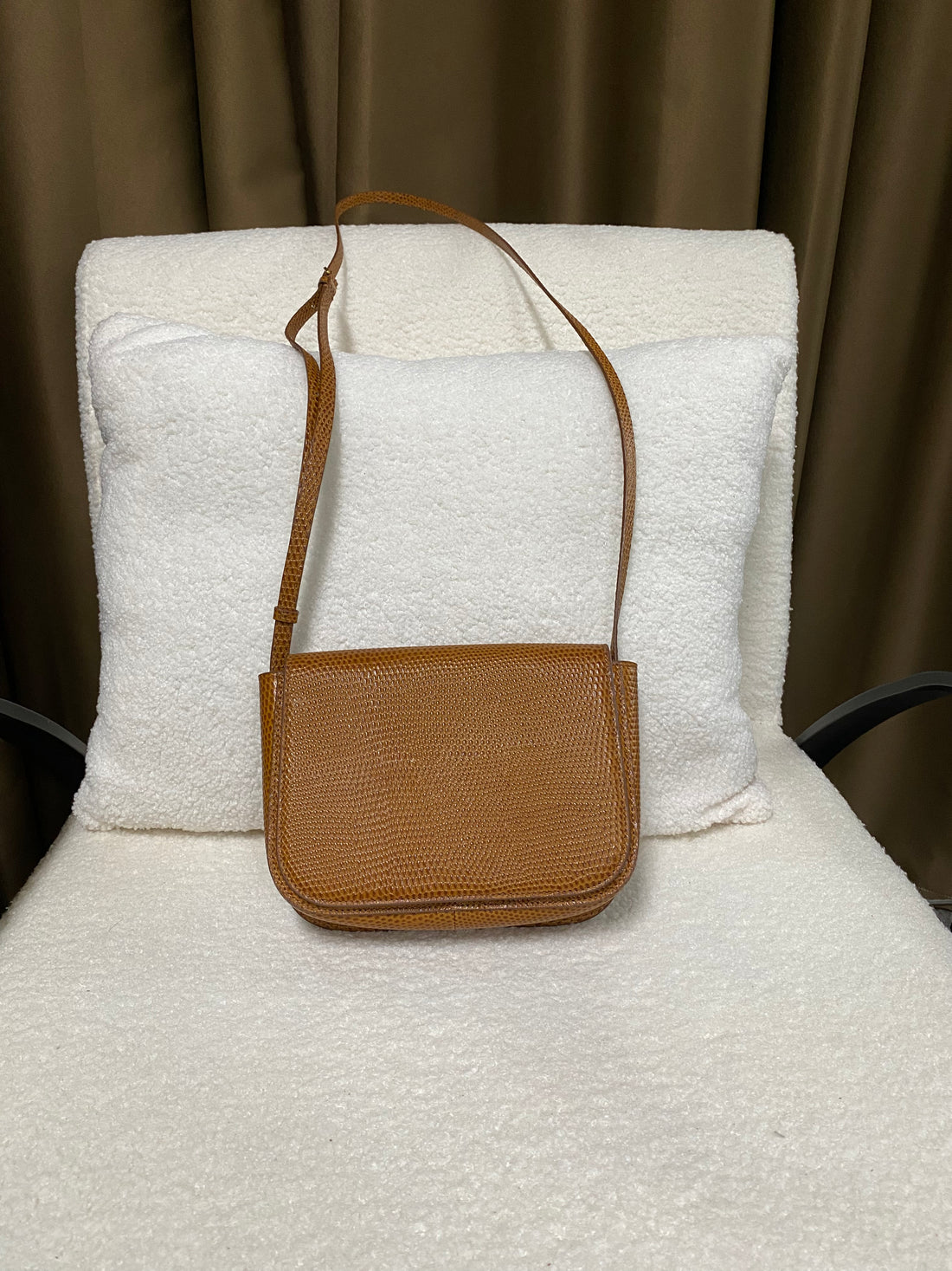 Tan lizard-embossed leather crossbody bag with adjustable strap, front view