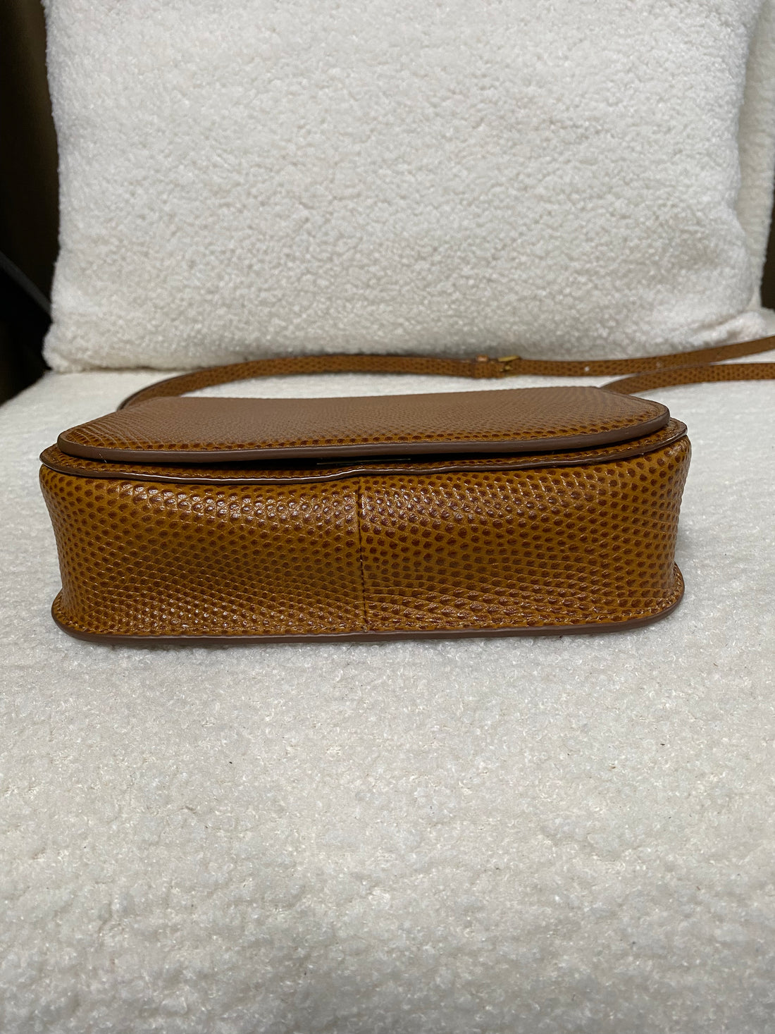 Bottom view of tan lizard-embossed leather crossbody bag showing structured base