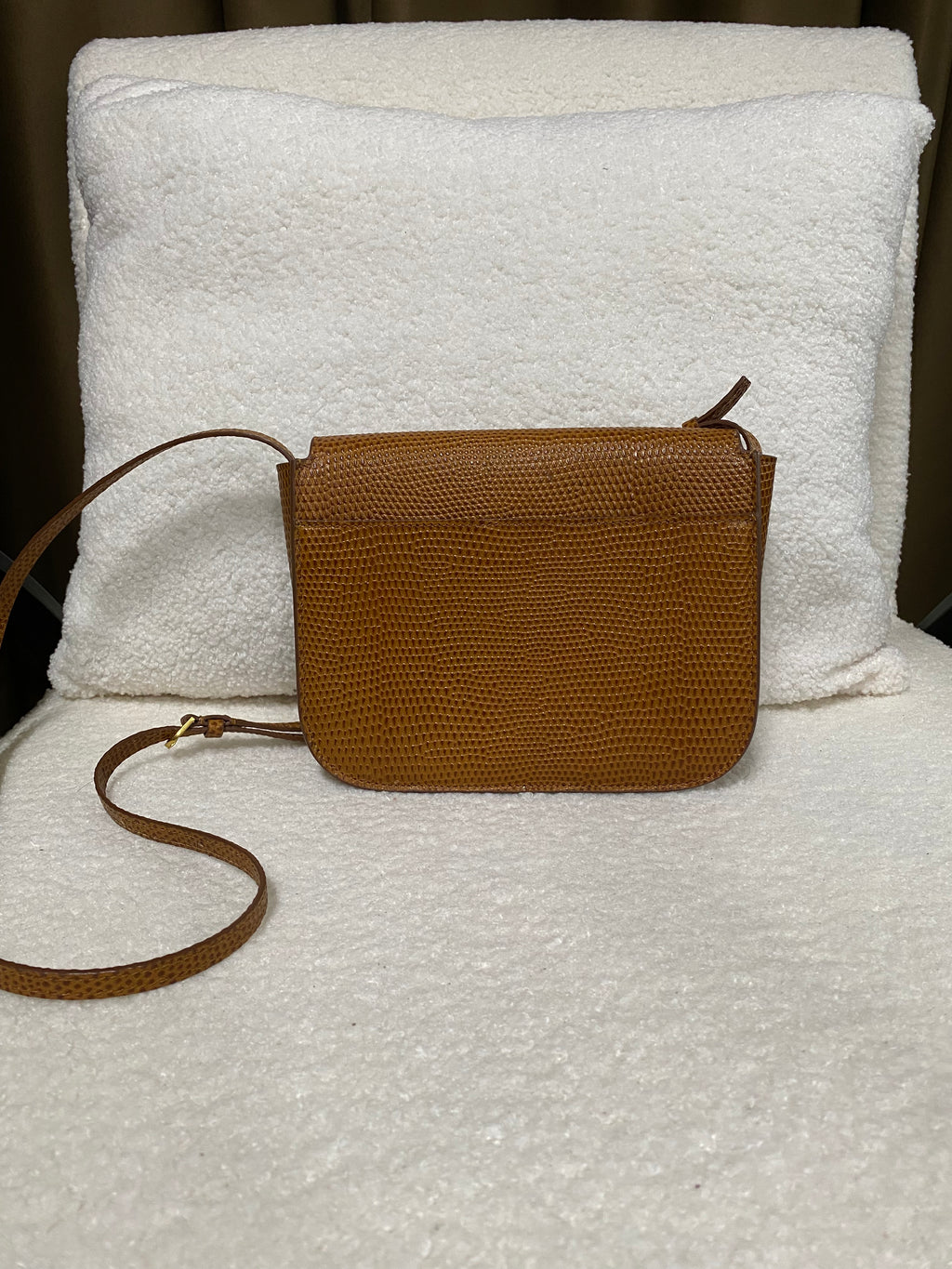Back view of tan lizard-embossed leather crossbody bag with adjustable strap