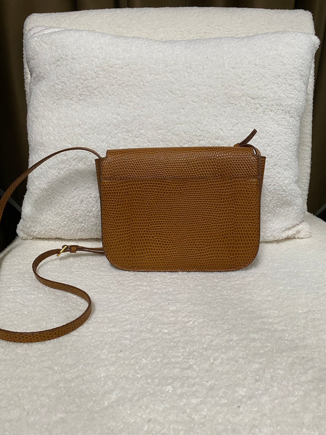 Back view of tan lizard-embossed leather crossbody bag with adjustable strap