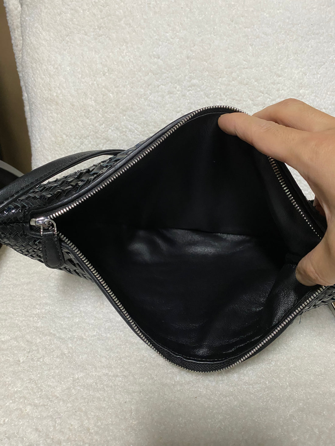 Open black-lined interior of woven leather hobo bag