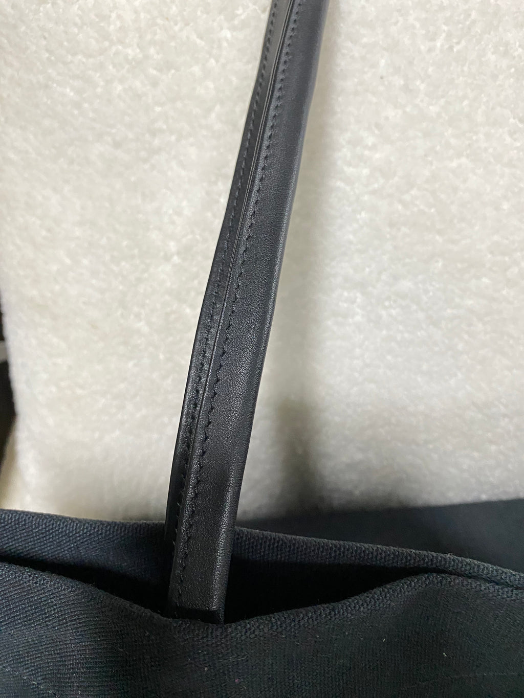 Stitched leather strap detail on navy canvas bag