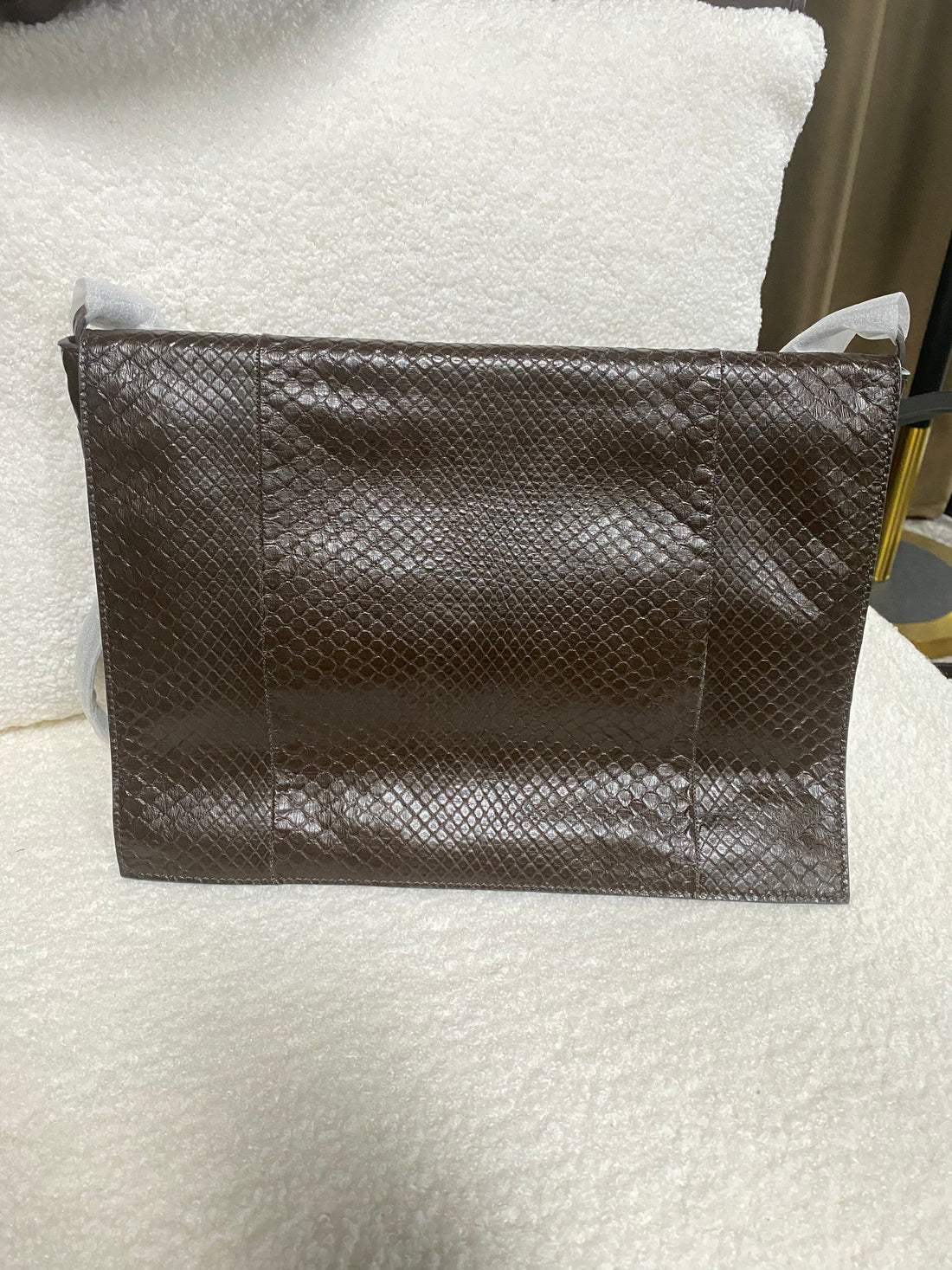 Brown genuine python leather shoulder bag — front view on a white chair