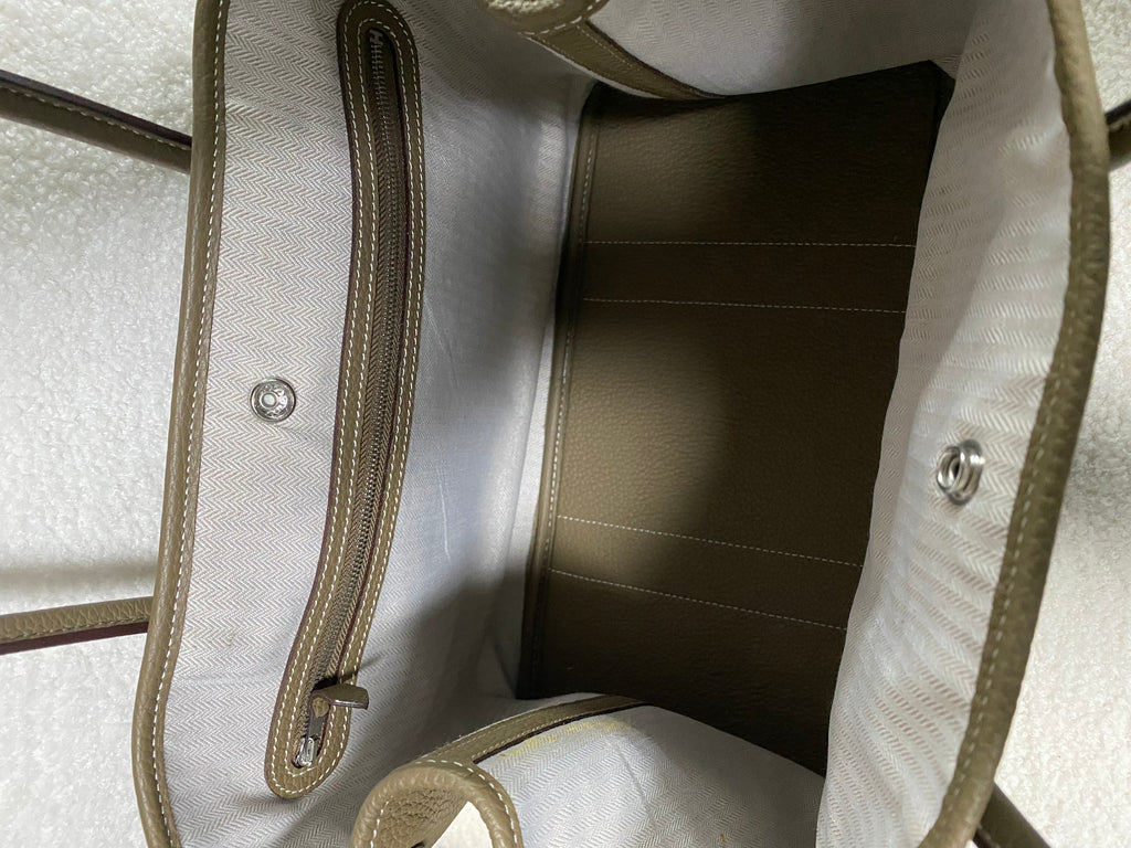 Open interior and snap closure of taupe leather tote