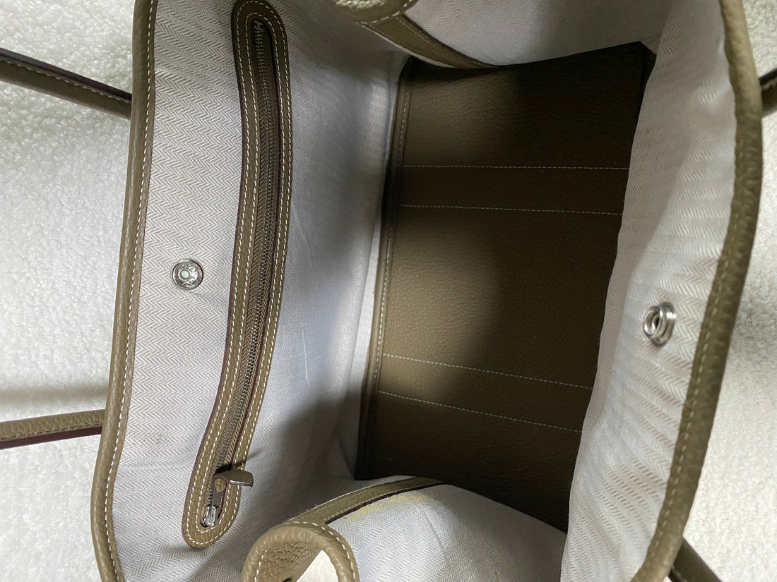 Open interior and snap closure of taupe leather tote