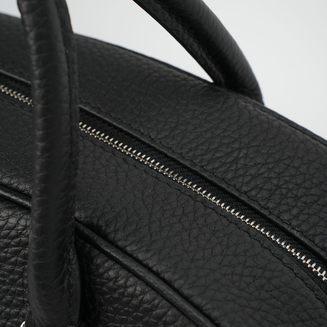 Logo-free full-grain cowhide top-handle bag — top zipper close-up