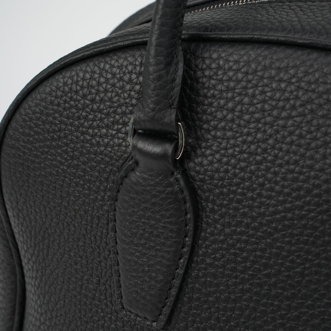 Logo-free full-grain cowhide top-handle bag — handle attachment close-up