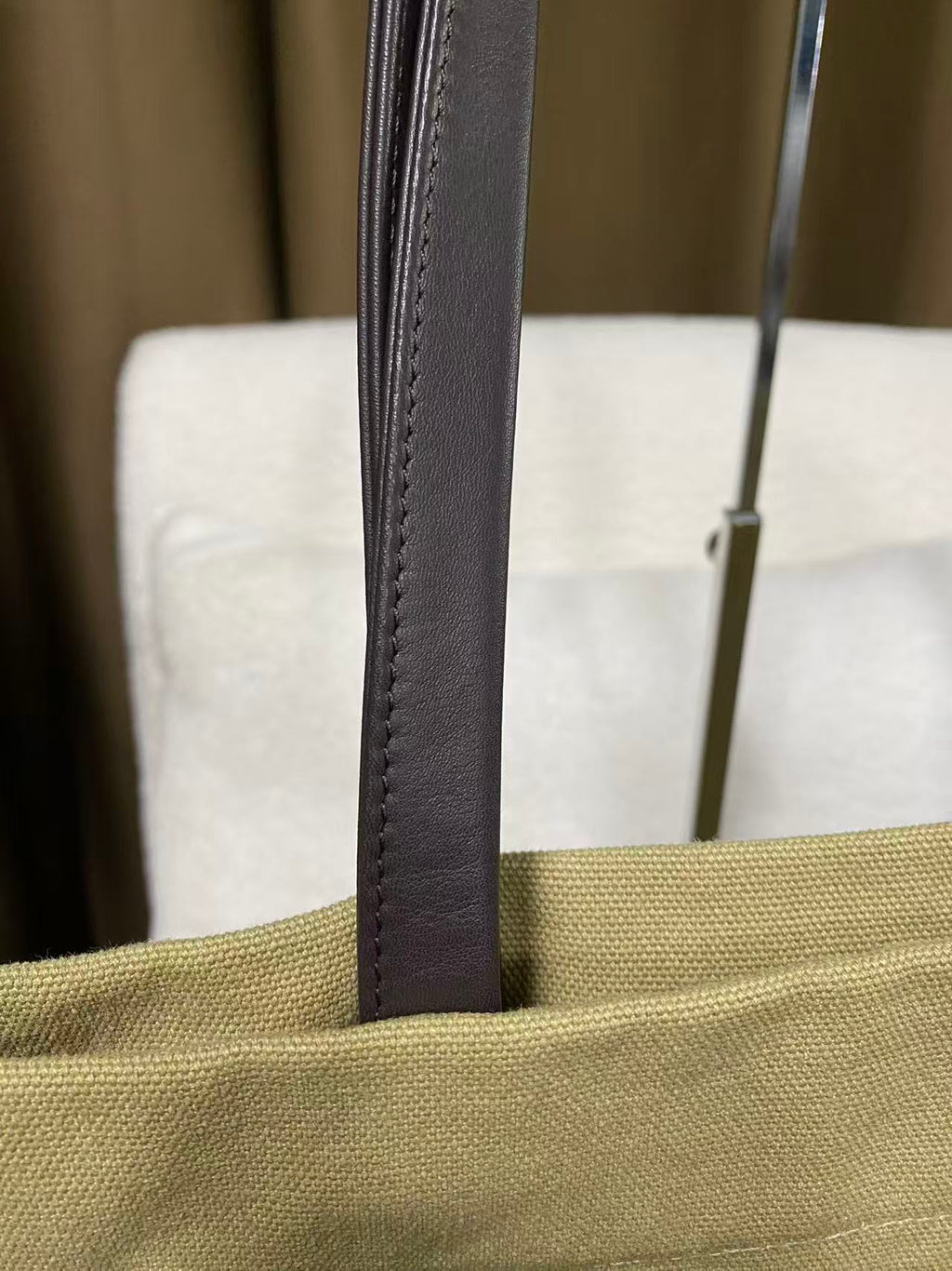 Dark leather shoulder strap on sand canvas shopper bag