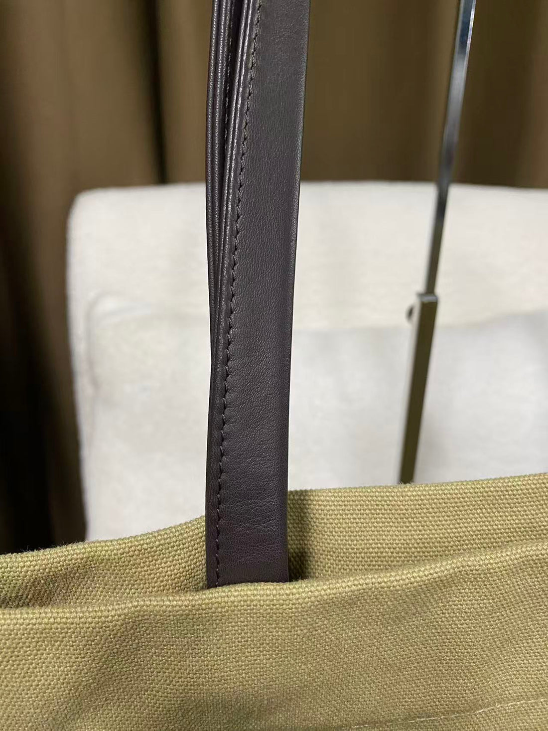 Dark leather shoulder strap on sand canvas shopper bag