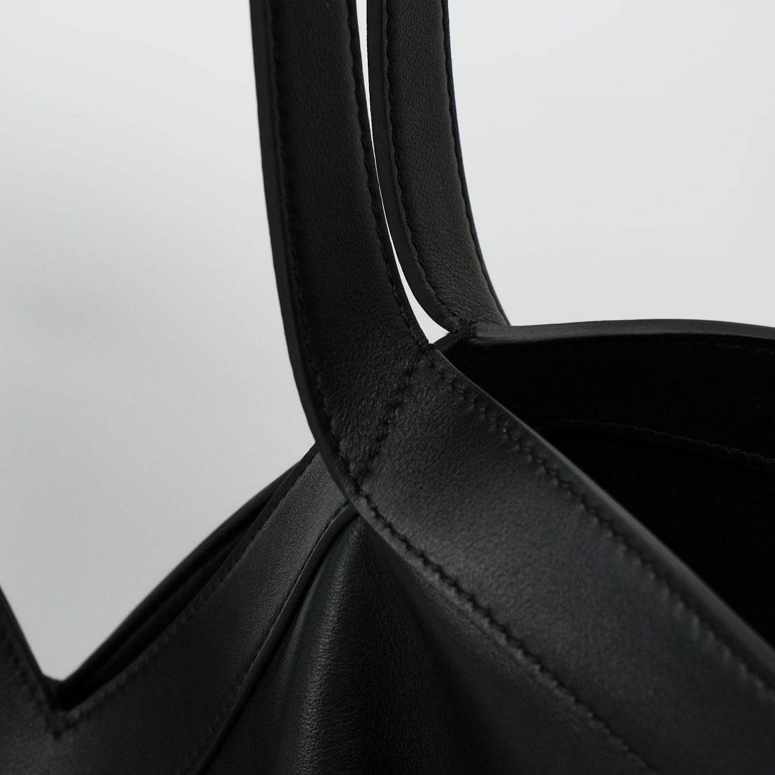 Logo-free black Y-strap slouchy leather tote — handle stitching close-up
