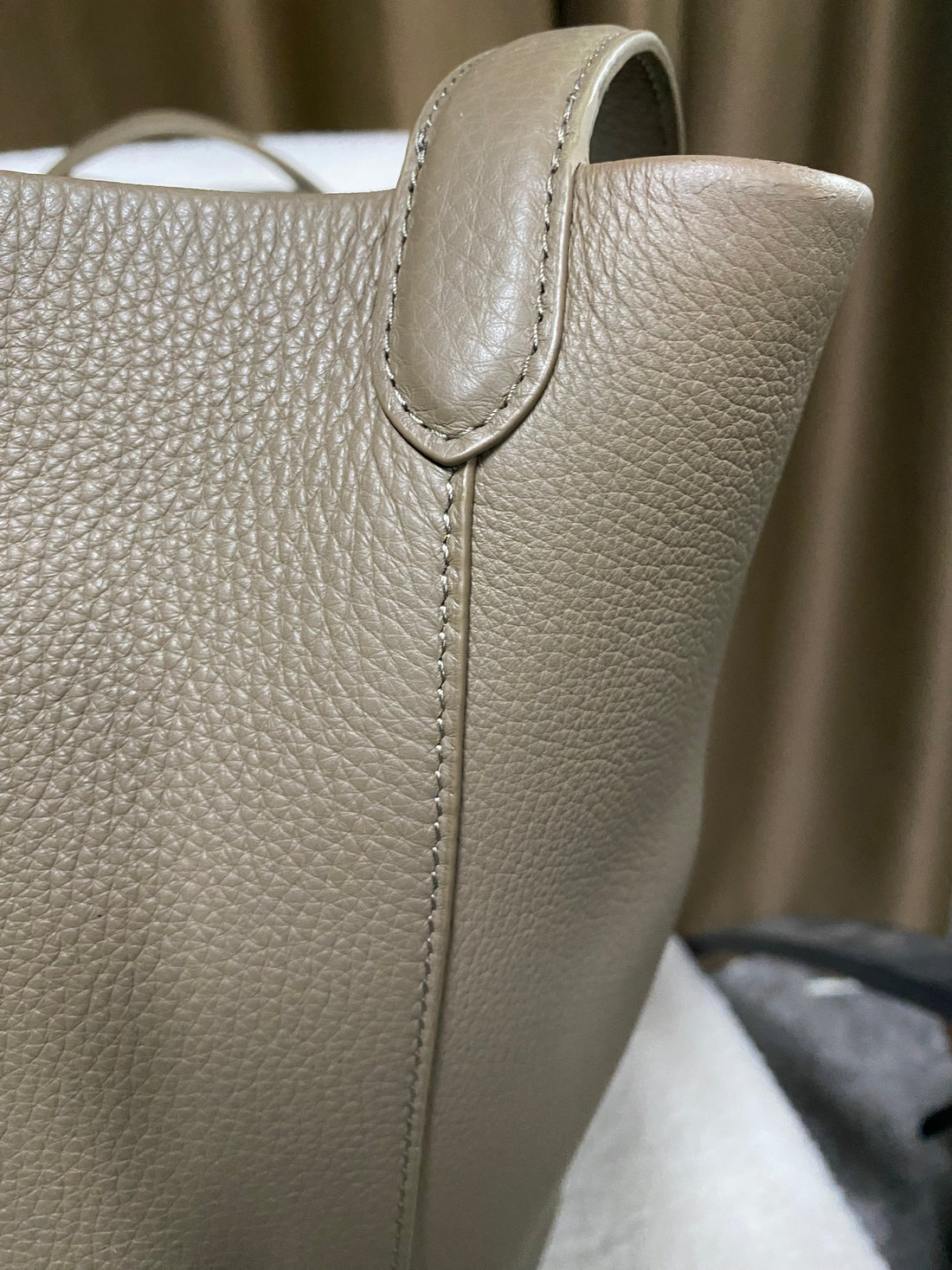 Pebbled cowhide texture and stitched strap detail on taupe bucket tote