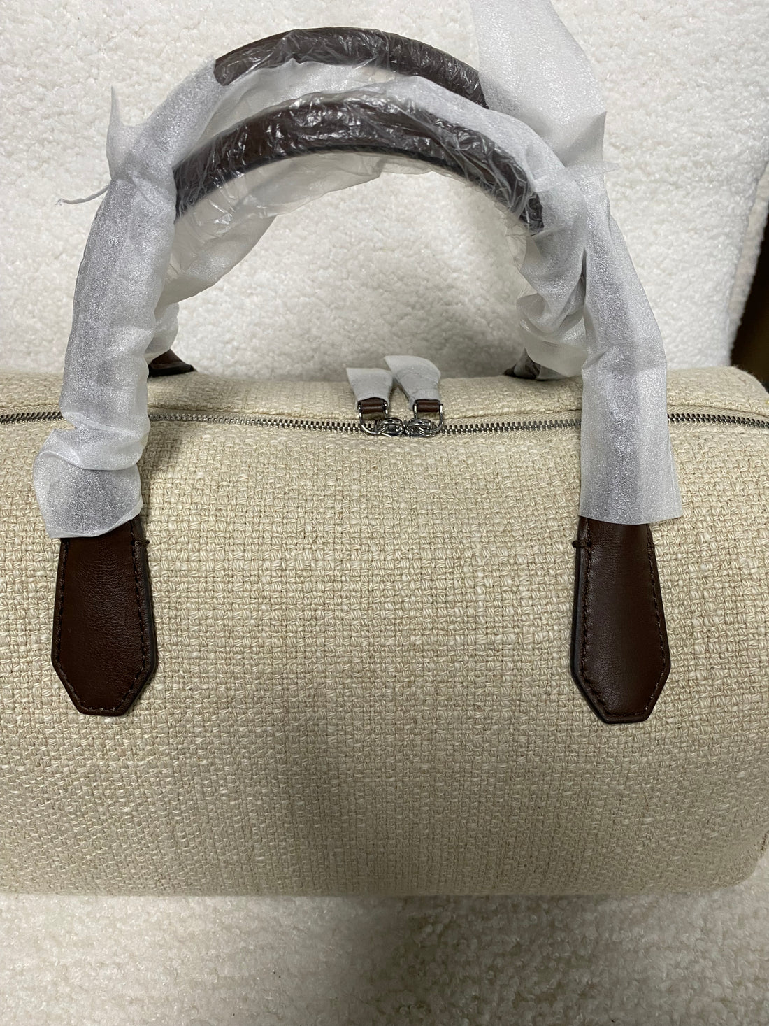 Top zipper and brown leather handles on linen Boston bag