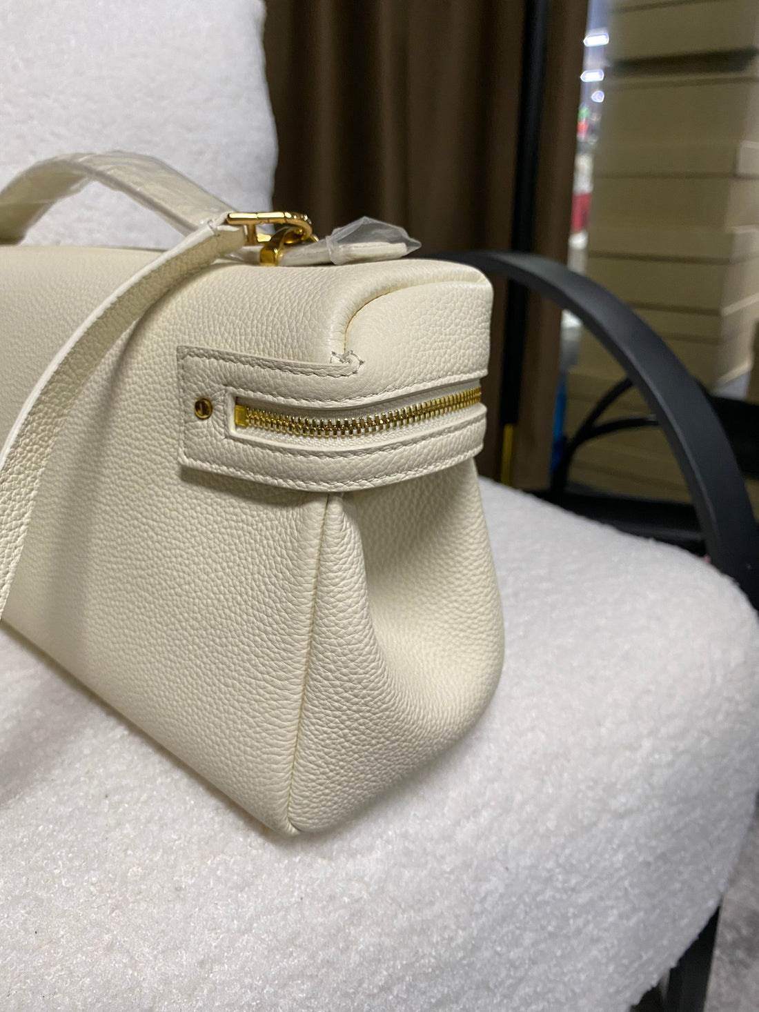 Side profile of cream leather handbag with exterior zipper pocket