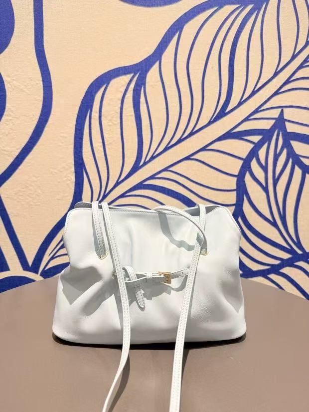Black ruched lambskin crossbody bag — white version displayed in a boutique