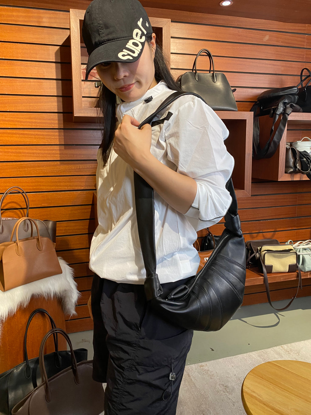 Logo-free lambskin croissant shoulder bag — black version worn crossbody in a boutique