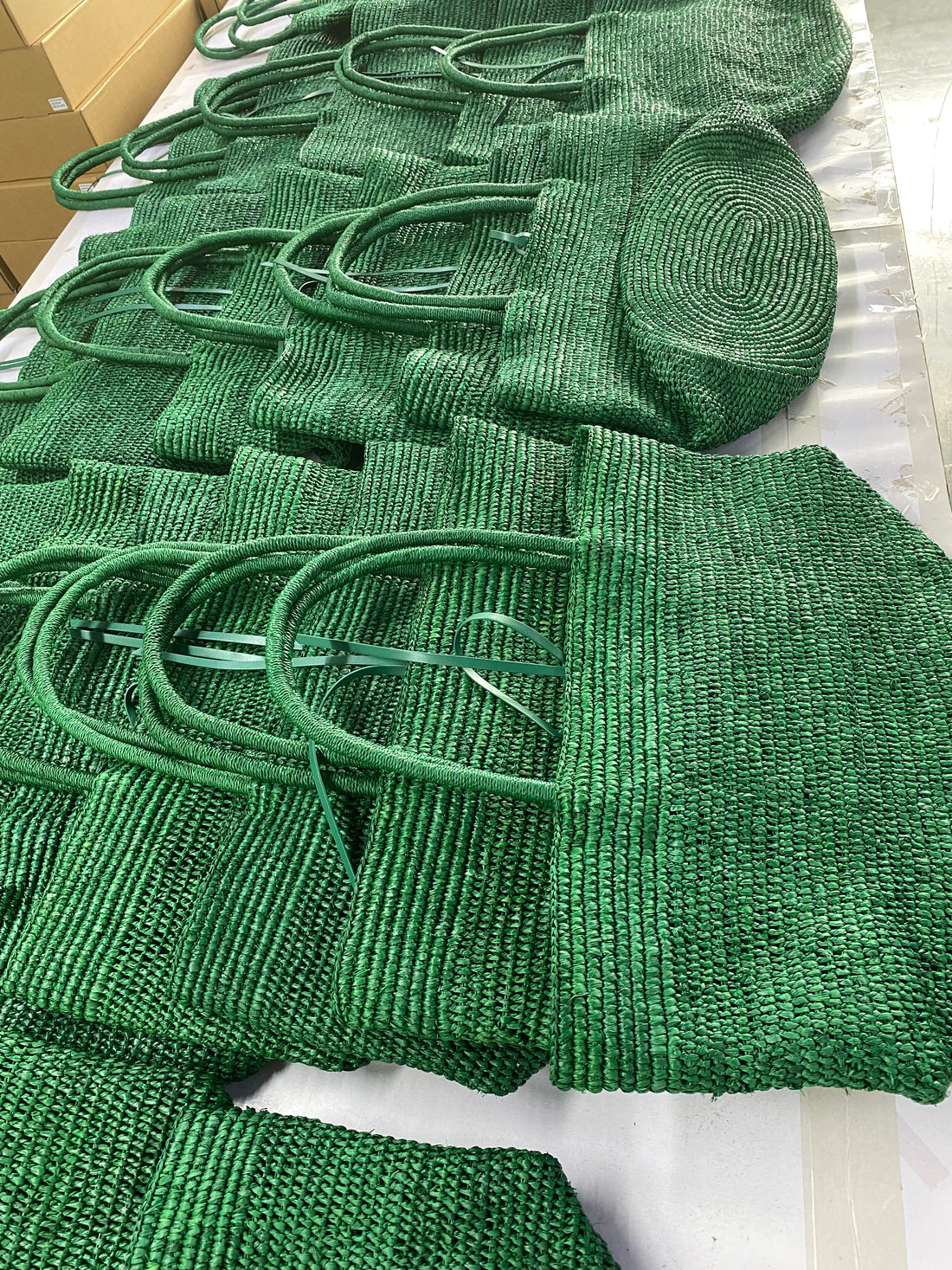 Emerald green woven raffia panels arranged on a workshop table