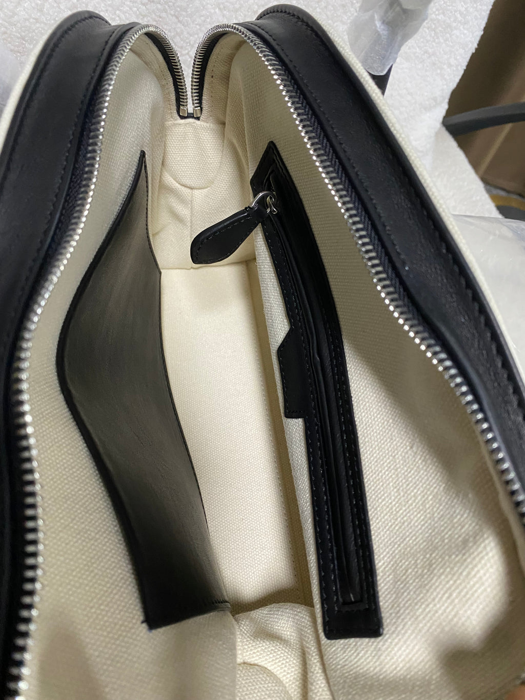 Open compartmented interior of cream linen and leather handbag