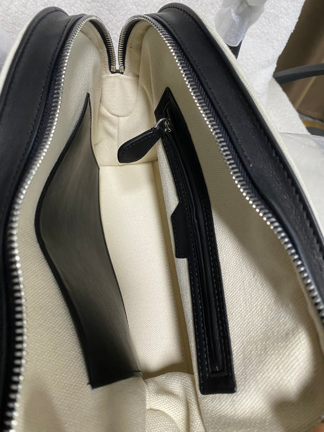 Open compartmented interior of cream linen and leather handbag