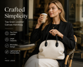 Woman carrying a cream linen handbag with black top-grain leather handles