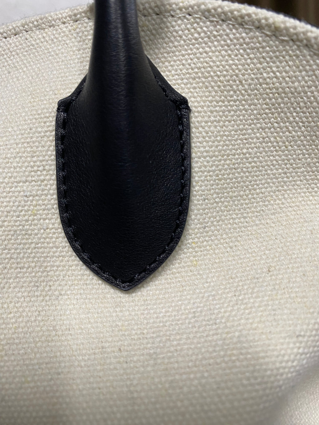 Black top-grain leather handle attachment on woven linen body
