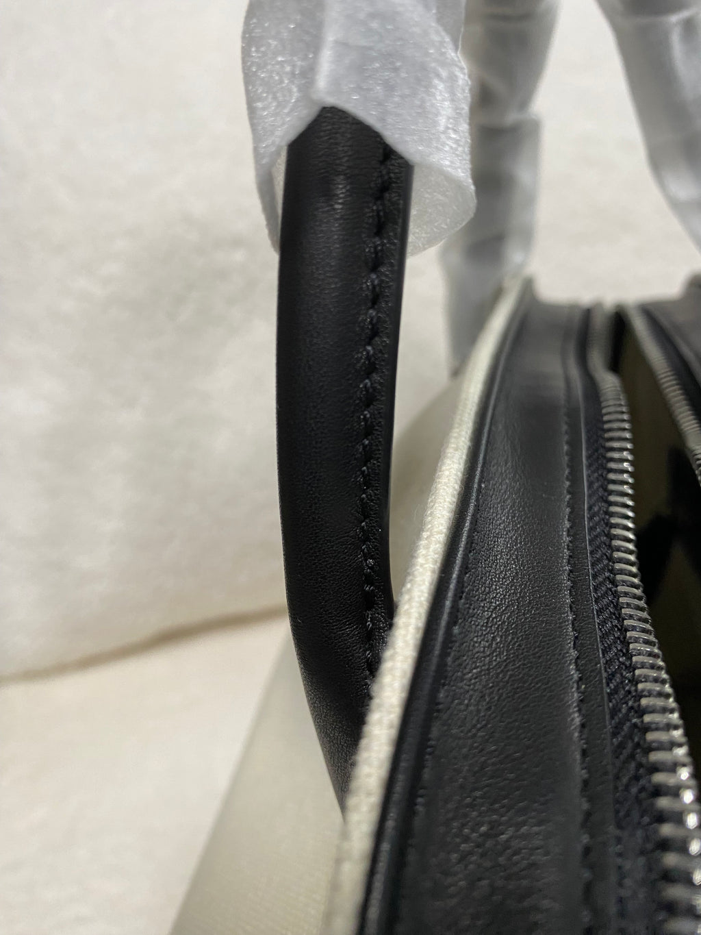 Black leather handle and zipper detail on cream linen handbag