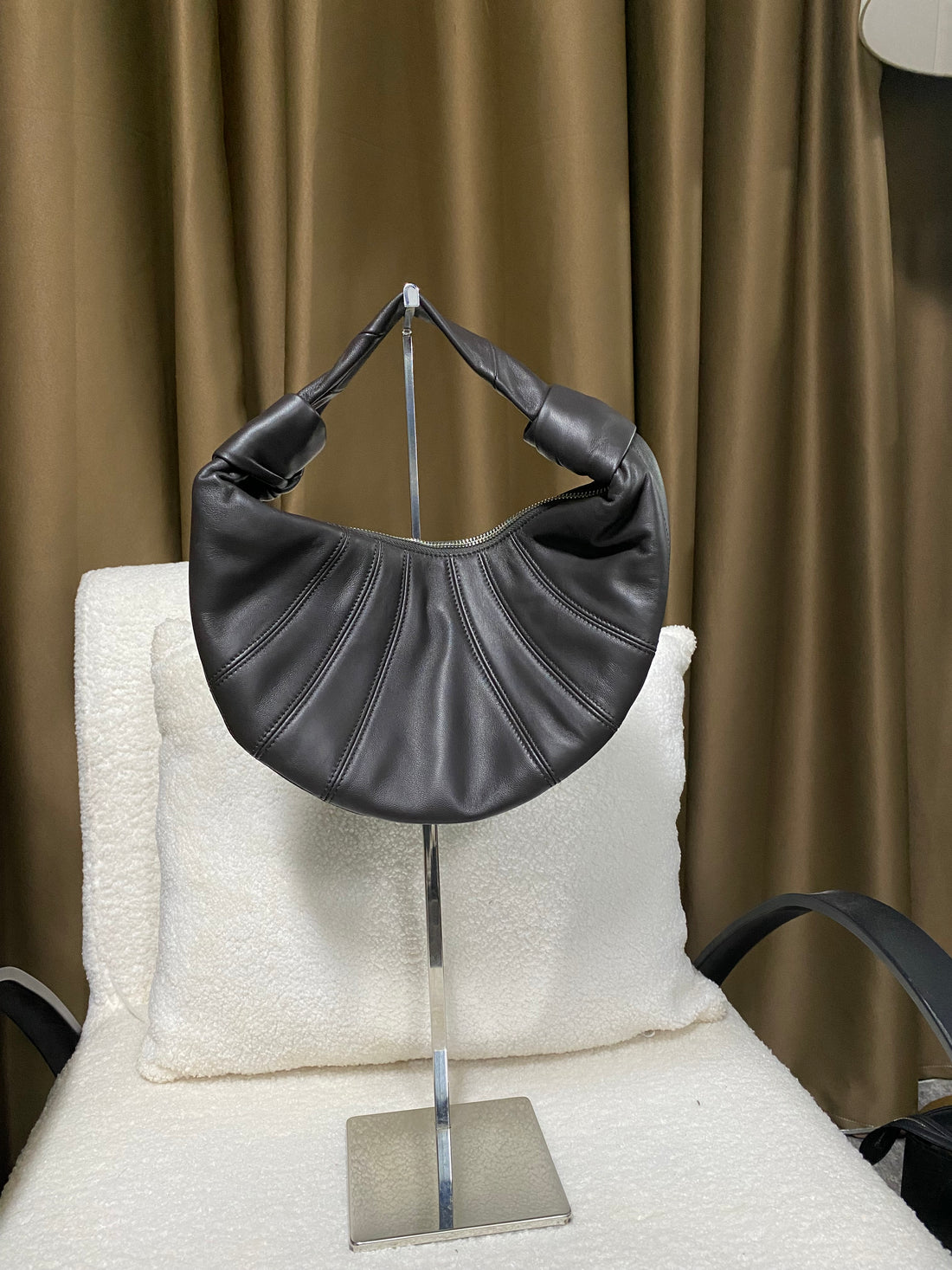 Black slouchy lambskin croissant bag hanging by its knotted handle