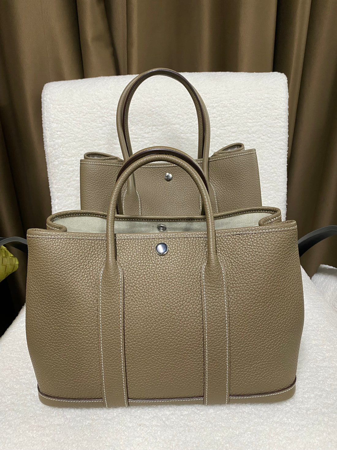 Three sizes of taupe wide-top leather snap tote