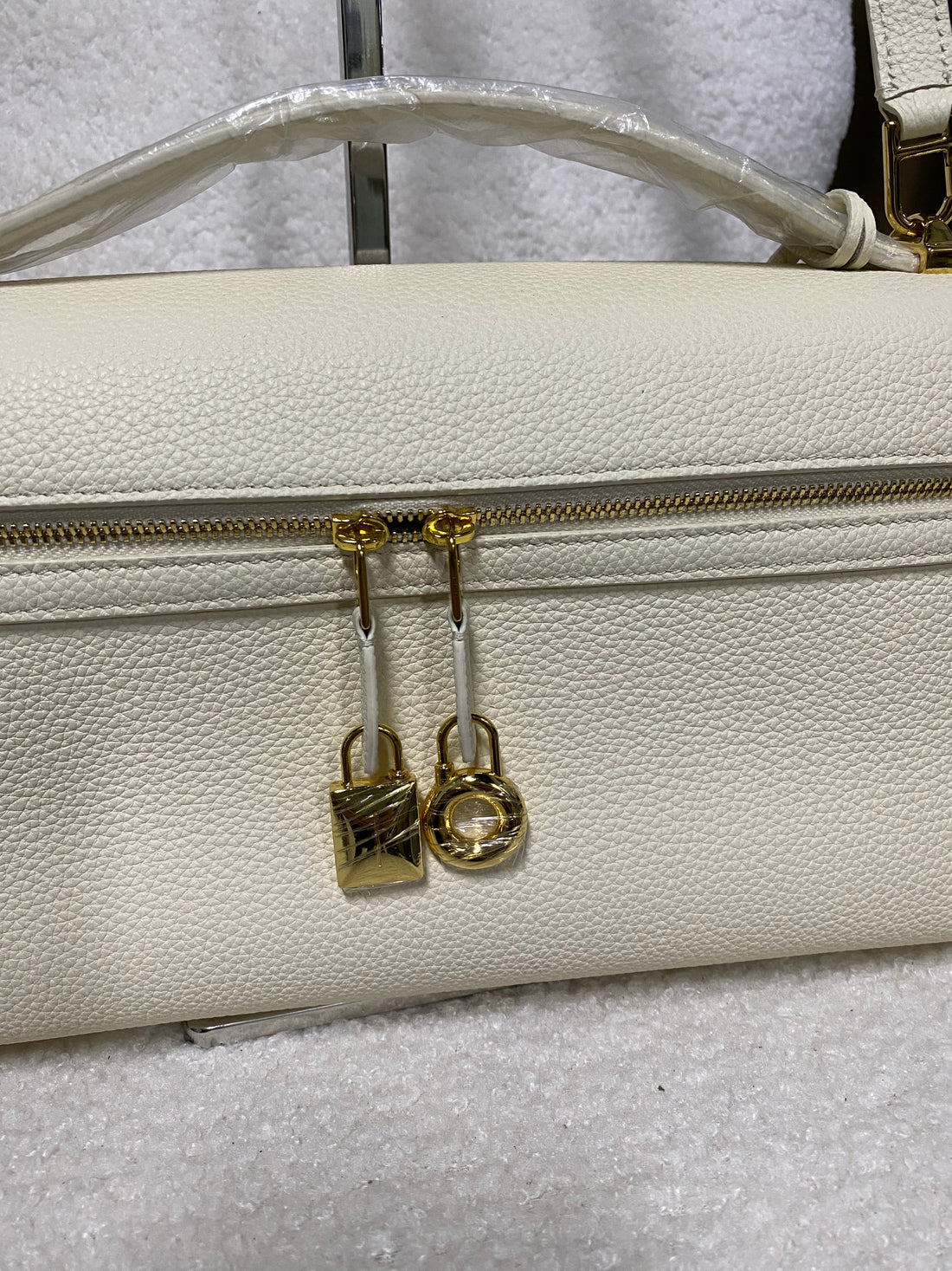 Gold double zipper and lock charms on cream leather bag