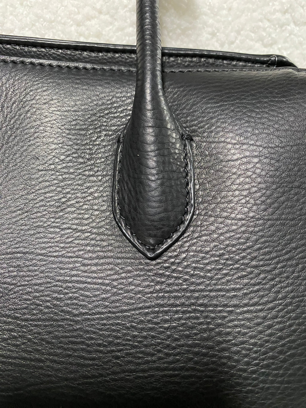 Natural pebbled calfskin texture and handle stitching close-up
