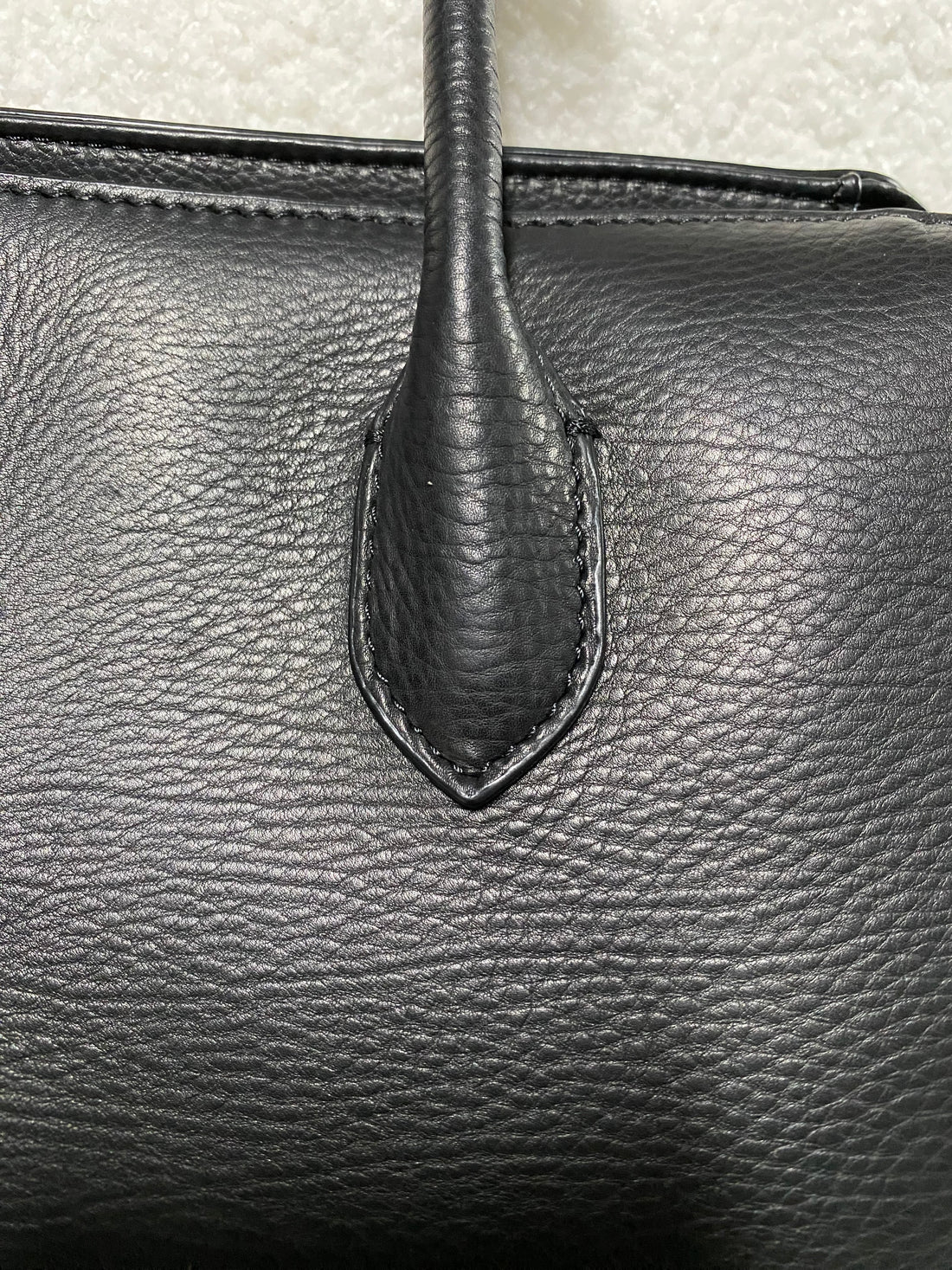 Natural pebbled calfskin texture and handle stitching close-up