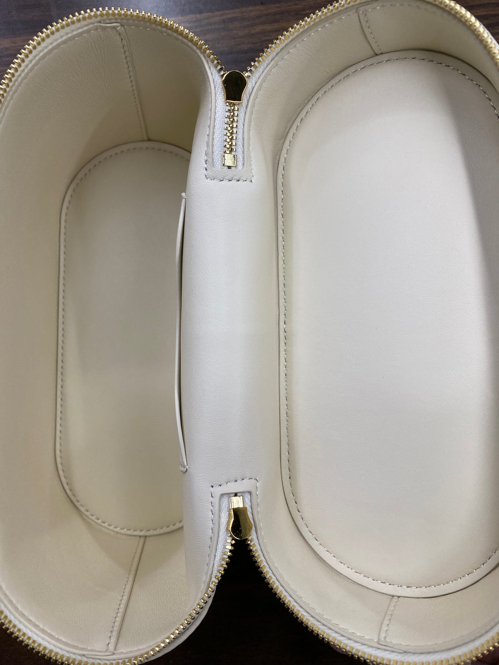 Open cream leather-lined interior of vanity case crossbody bag