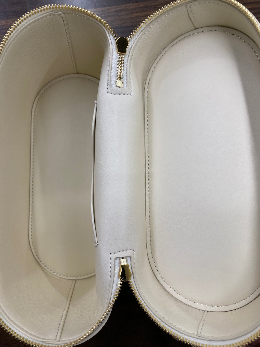 Open cream leather-lined interior of vanity case crossbody bag