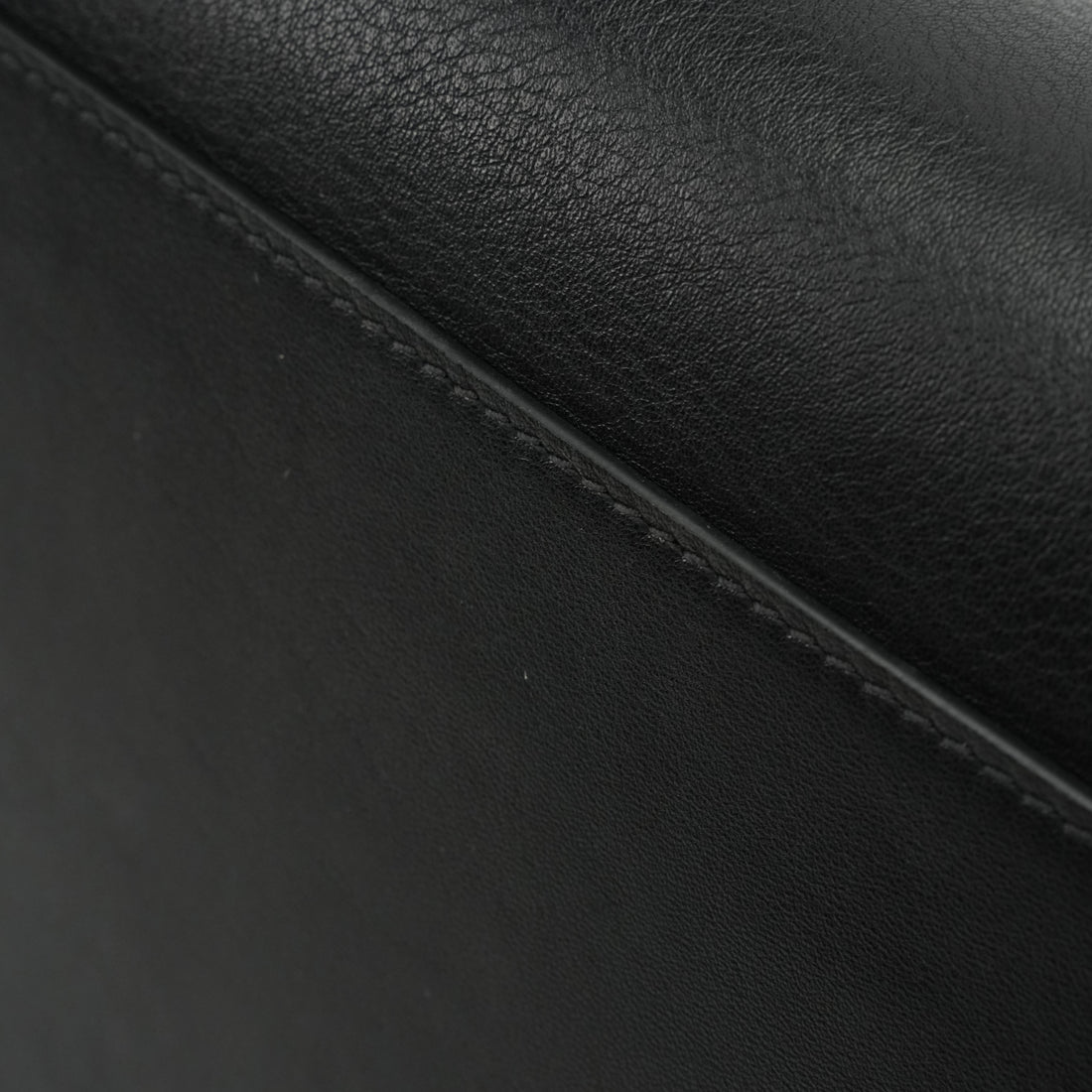 Logo-free black cowhide work tote — smooth leather grain and stitching close-up