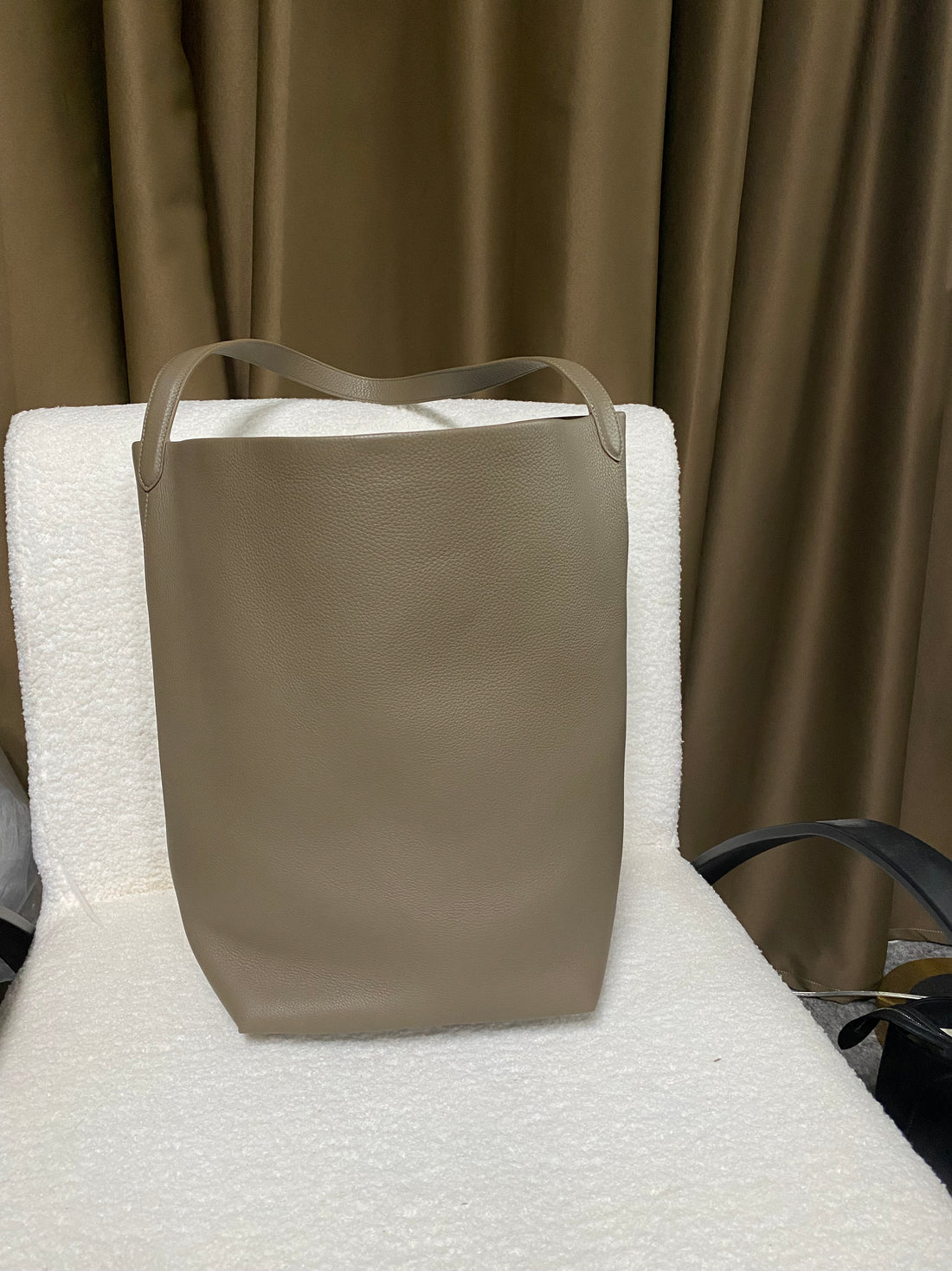 Taupe-grey leather bucket tote back view with wide shoulder strap