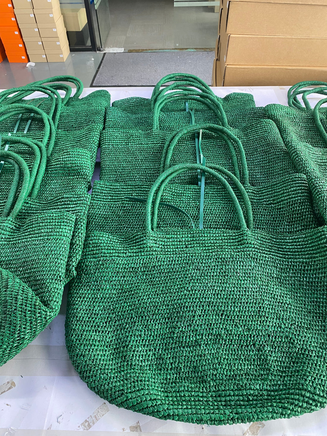 Emerald green raffia tote bodies lined up on the workshop table