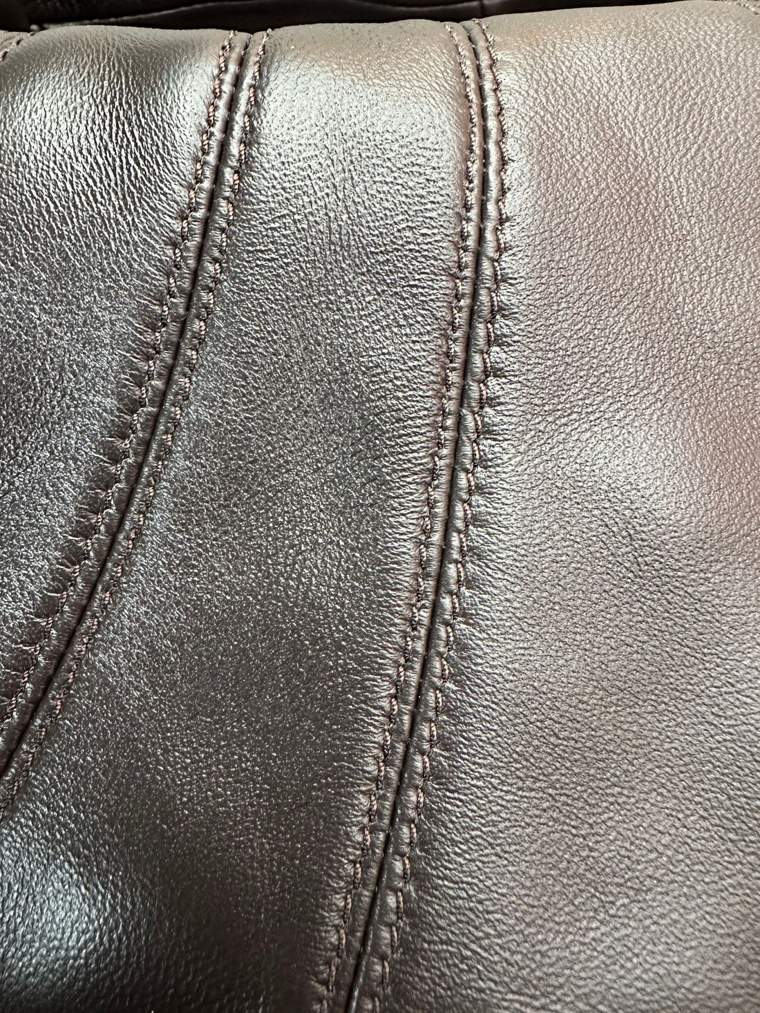Logo-free lambskin croissant shoulder bag — dark brown lambskin texture and stitching close-up